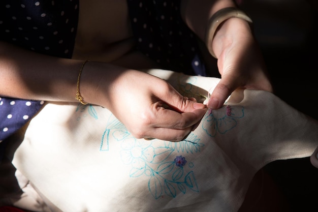 hands embroidering detailed pattern